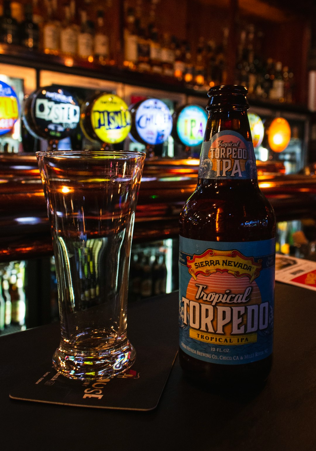 Tropical Torpedo liquor bottle beside clear drinking glass