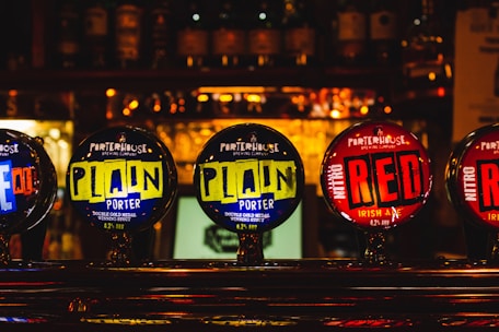 Close-up of frothy pints of golden Irish beer against a backdrop of dark oak bar and green Irish decor.