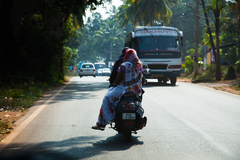 deux personnes conduisant une moto sur la route pendant la journée