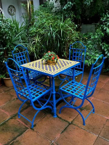 Close-up of a 5-piece outdoor dining set with vibrant cushions on a stone patio.