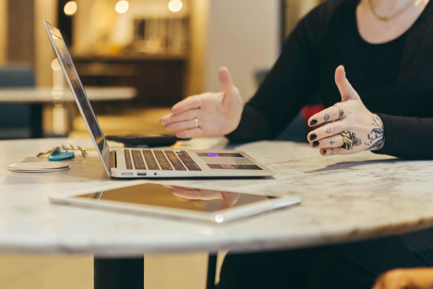 Laptop and tablet on a table while a person gestures