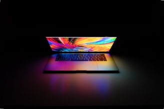 Modern laptop screen displaying dynamic code and data streams in vibrant neon colors.
