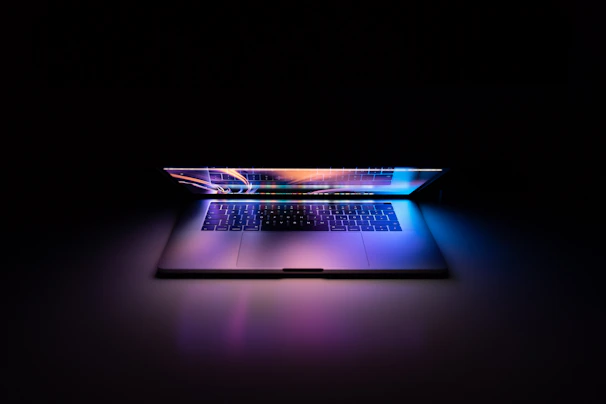 A stylish laptop with colorful backlit keyboard open on a minimalist workspace.