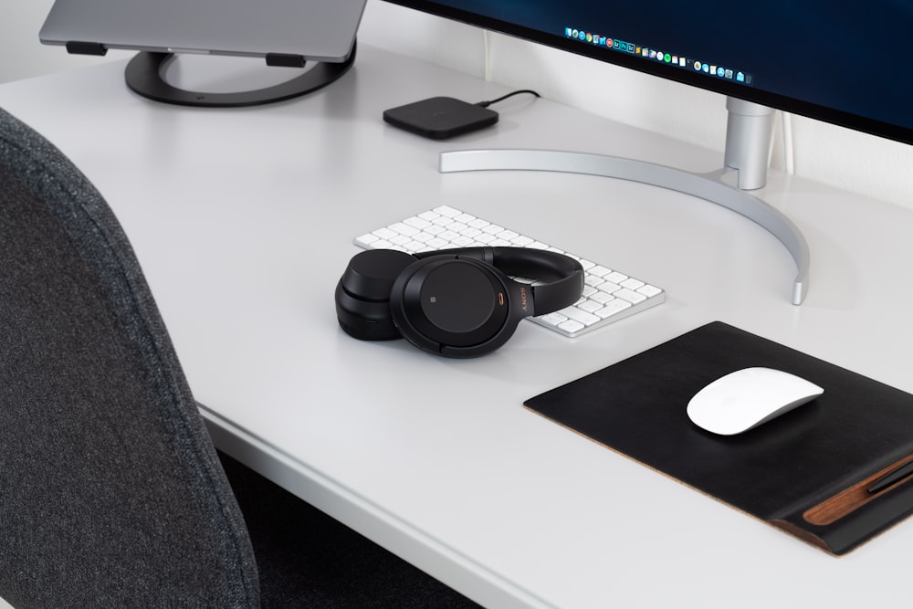 wireless headphones and Apple Magic mouse in front of iMac placed on desk