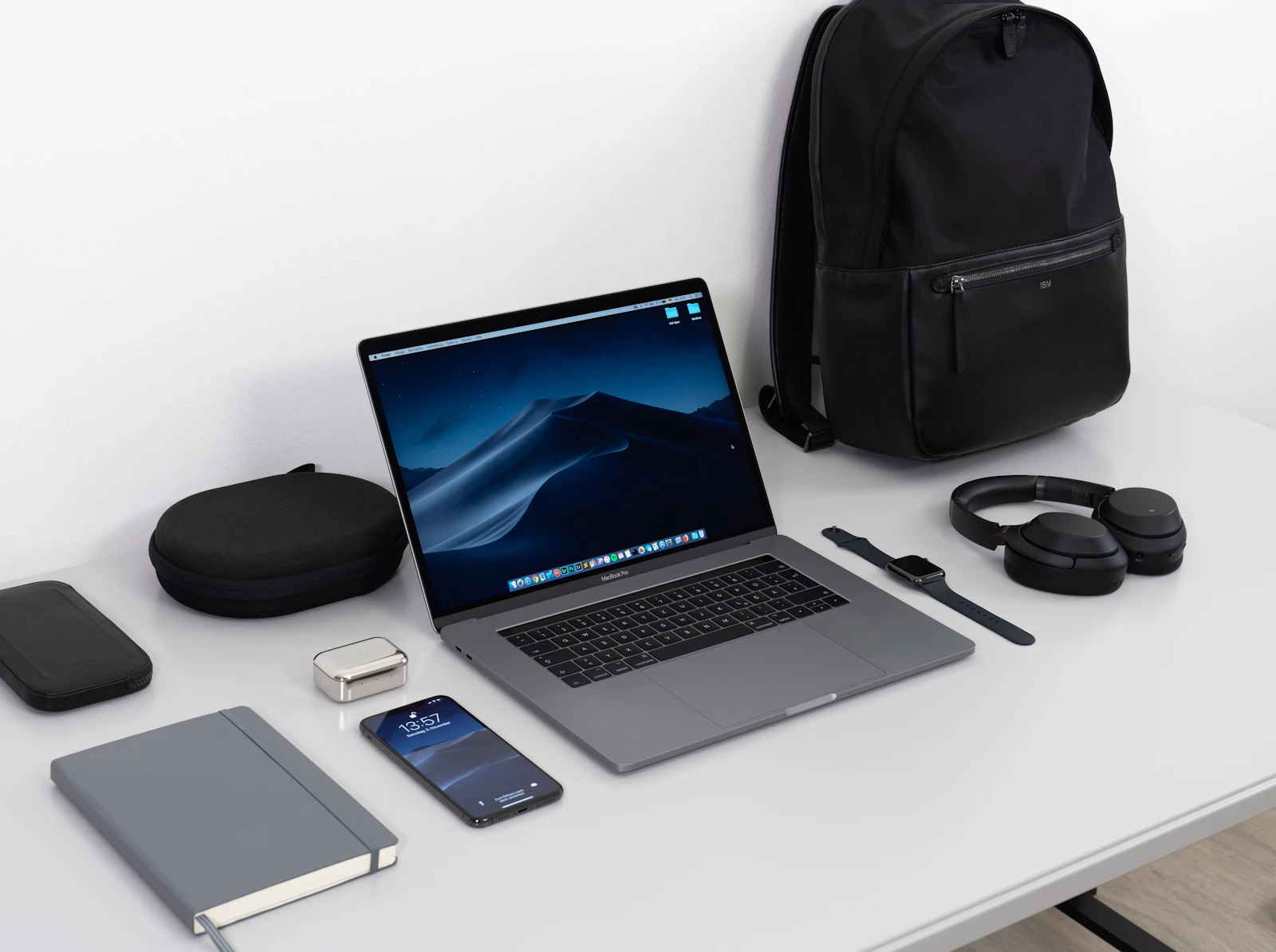 Travel tech essentials arranged with a laptop, headphones, and backpack