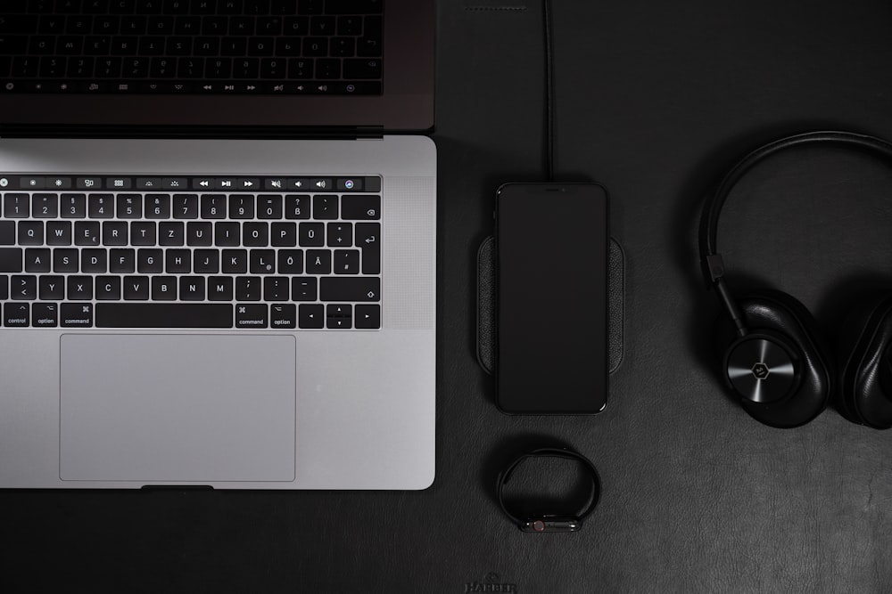 silver MacBook Pro beside phones