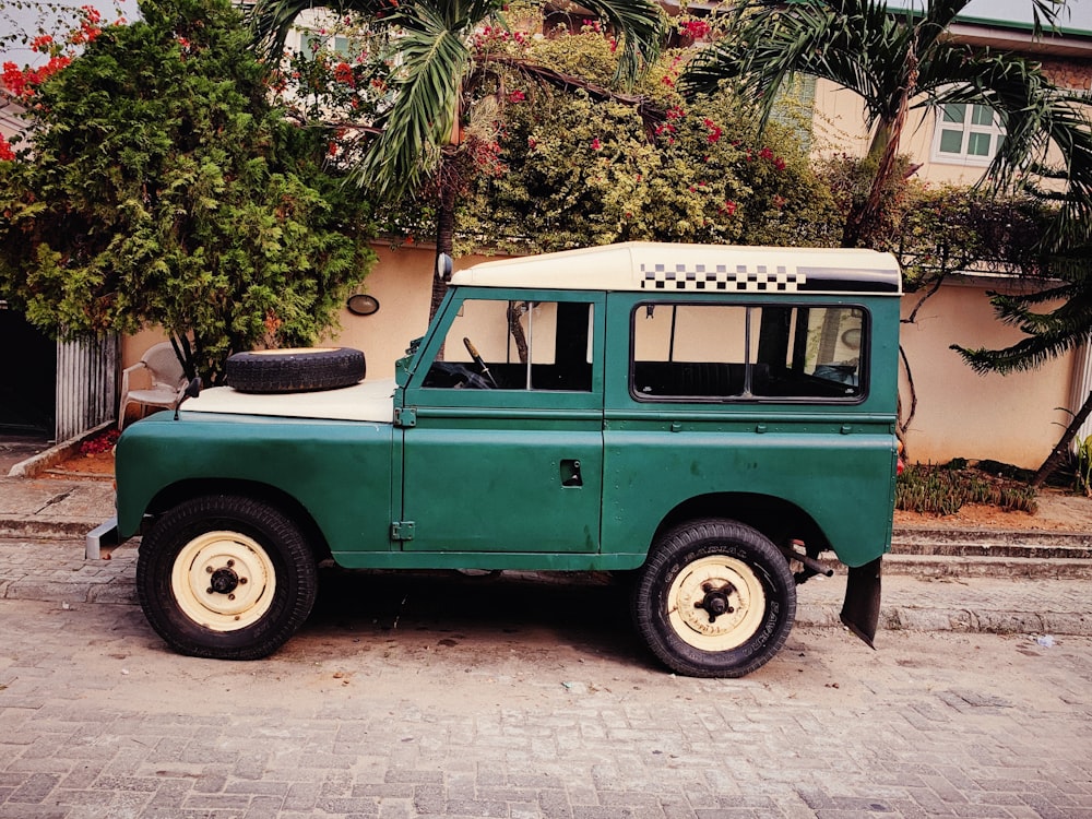 green and white off-road vehicle parked outside wall near trees