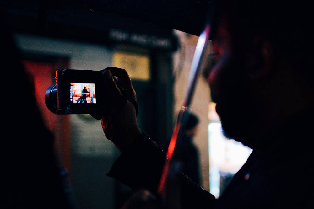 person under the umbrella holding digital camera