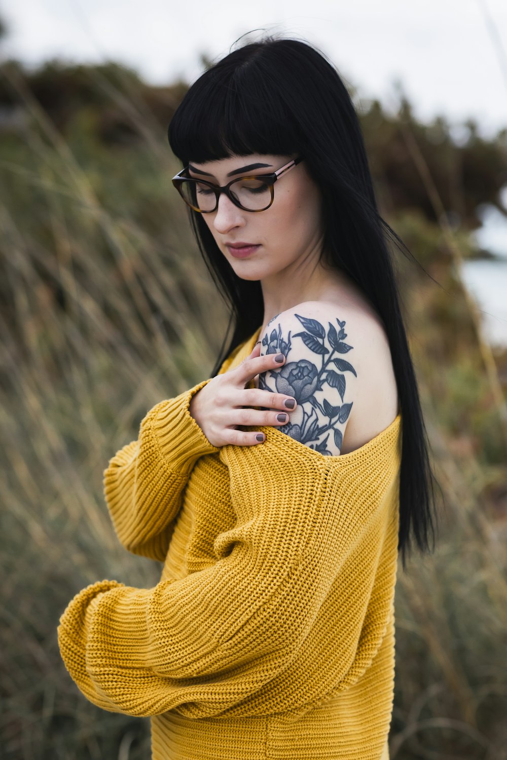 woman wearing yellow sweater showing her rose flower arm tattoo