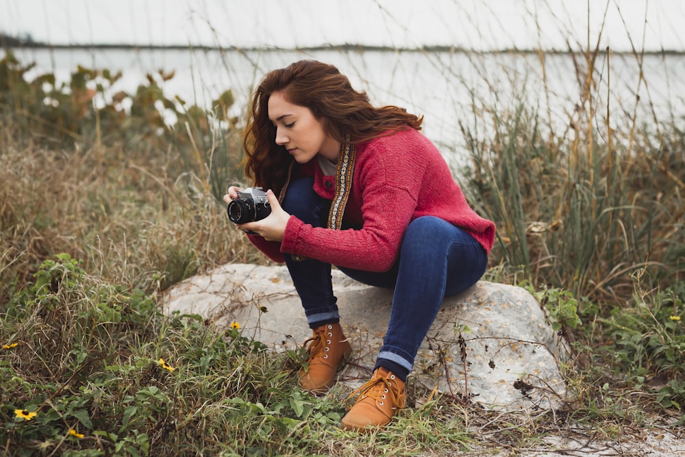 woman taking photo of grass using bridge camera during daytime