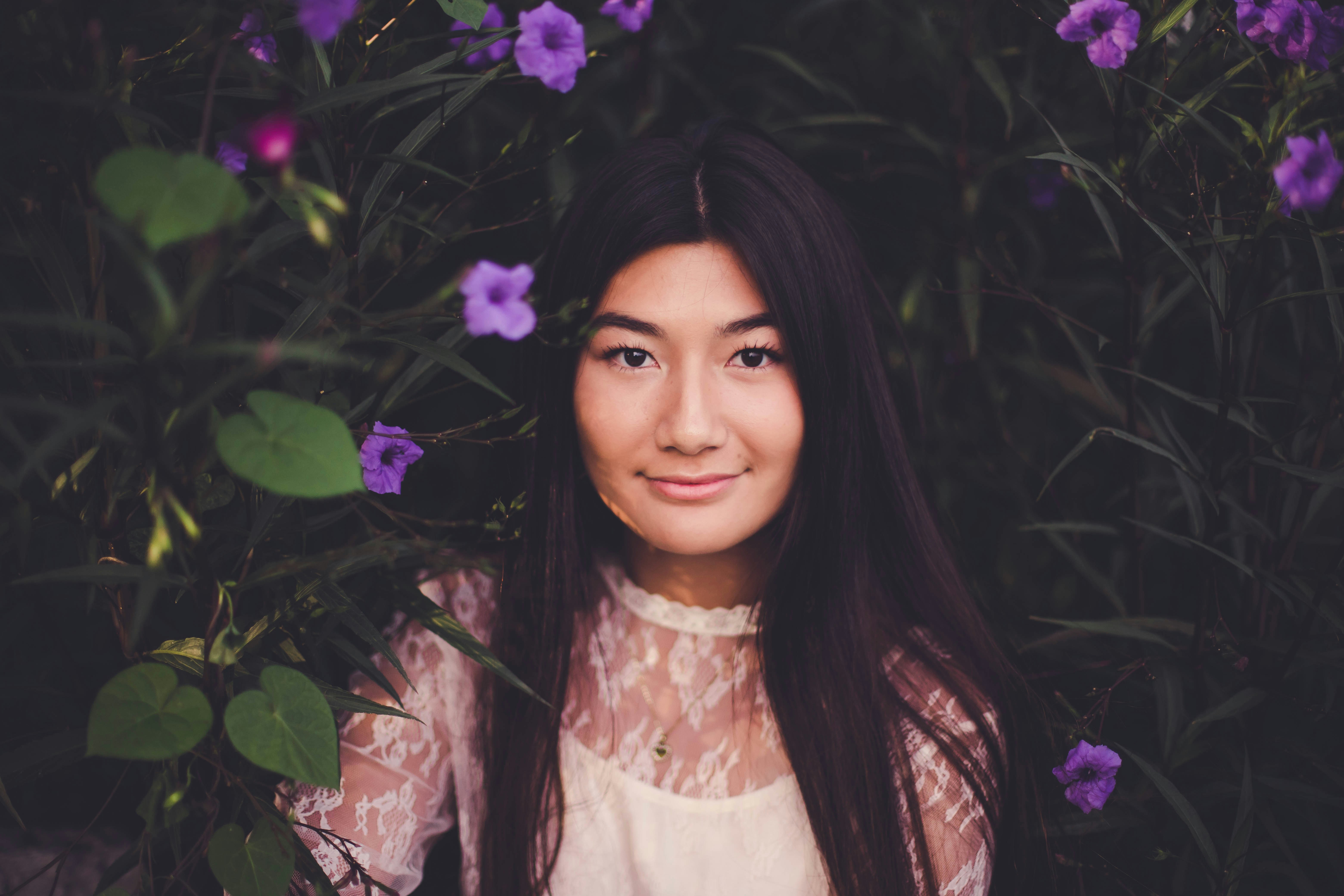smiling woman leaning on purple flower