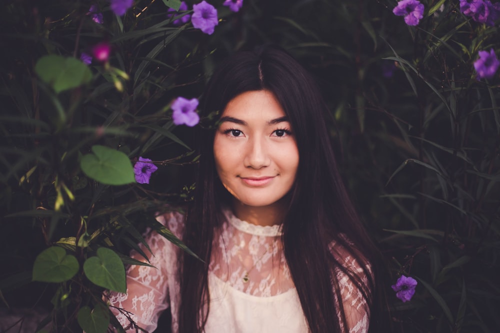 smiling woman leaning on purple flower