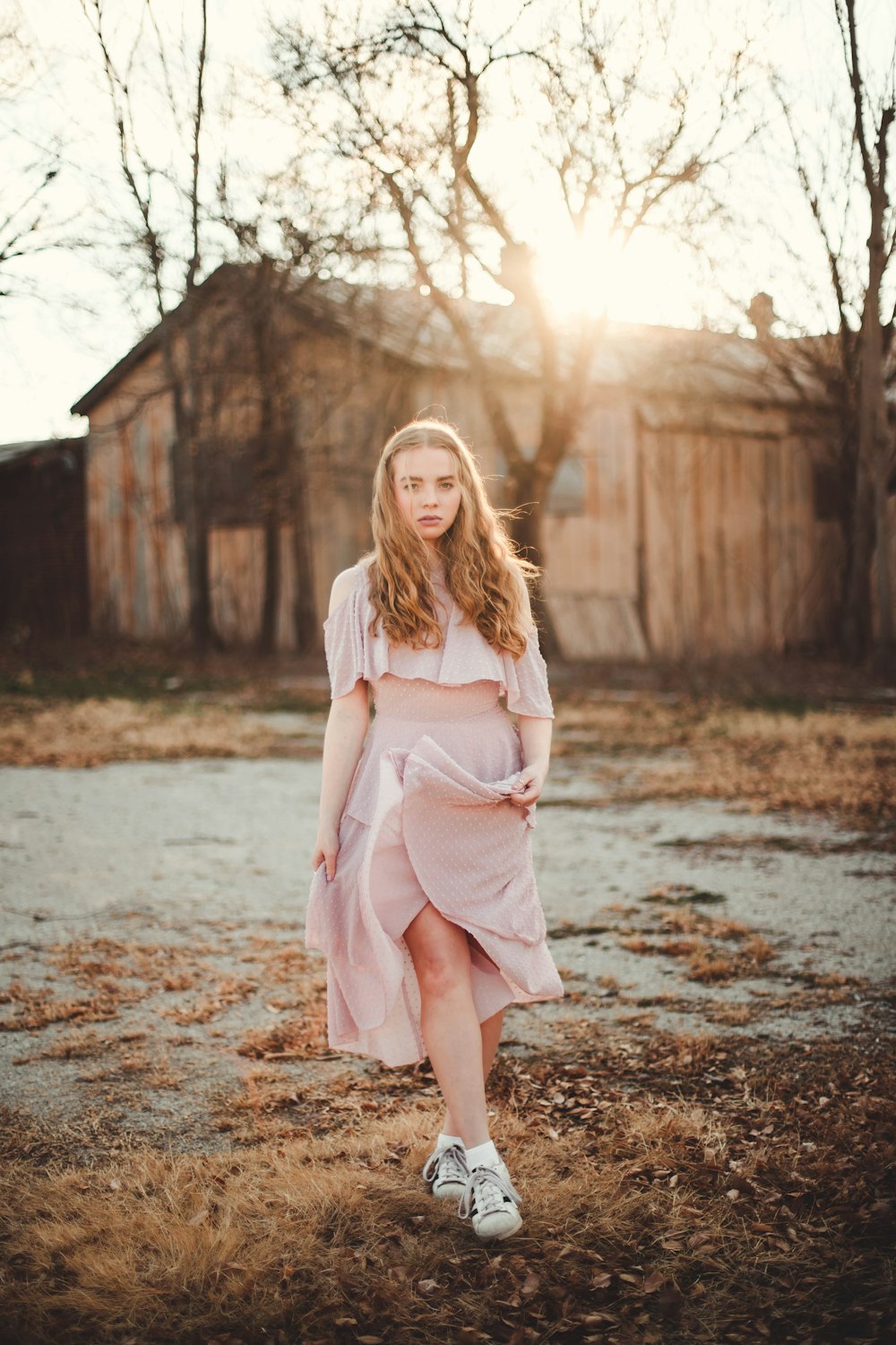 woman in white crop top with skirt walking on brown dried grass field