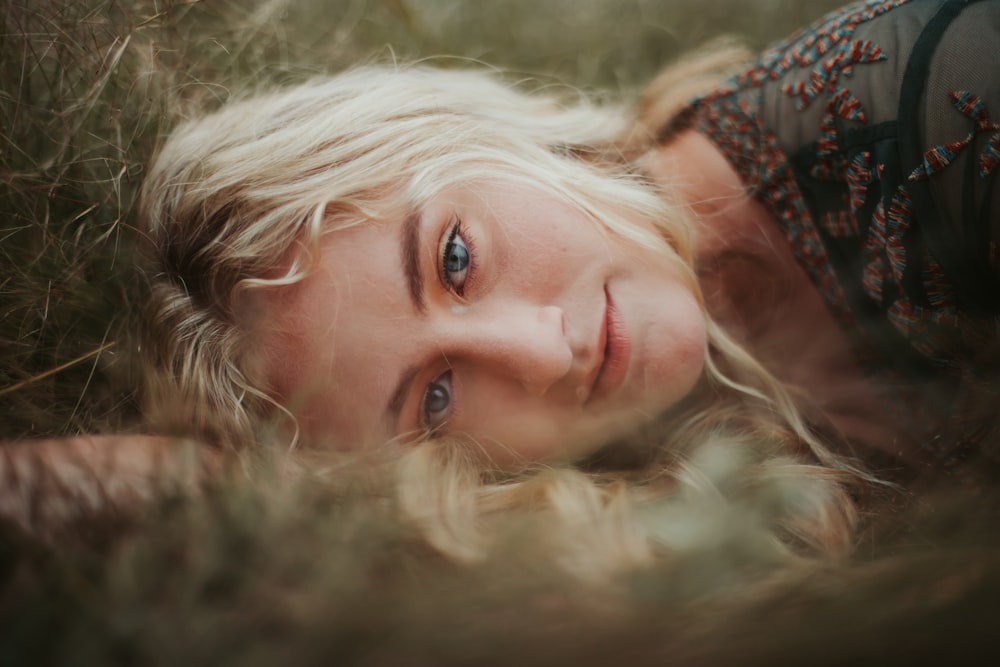 selective focus photography of woman lying on grass field
