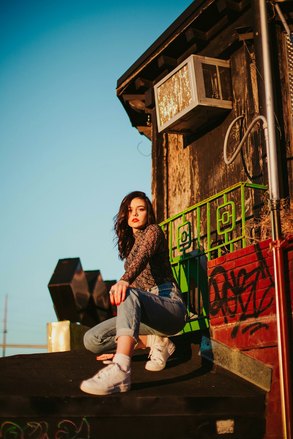 girl in brown dress shirt crouching under blue sky