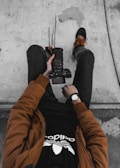 man sitting on concrete ground while holding DSLR cameraa