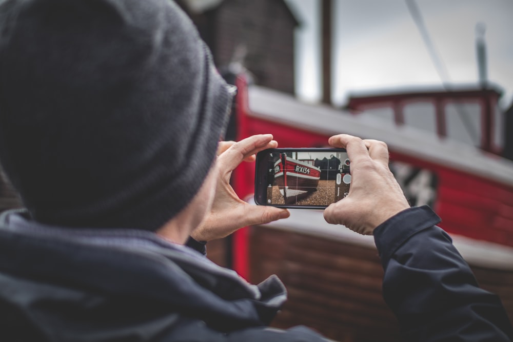 Fotografia selettiva della messa a fuoco della persona che scatta la foto della bancarella rossa usando lo smartphone durante il giorno