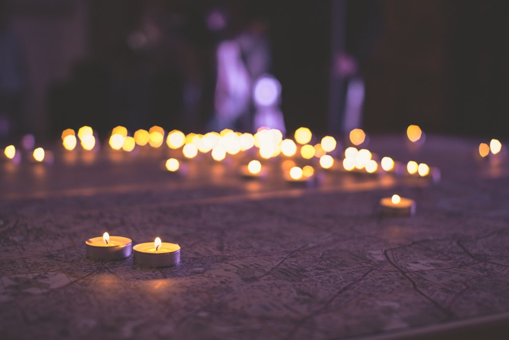 two votive candles on tabletop with bokeh lights