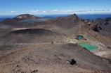 Tourists hiking a scenic trail with panoramic views of volcanic mountains.