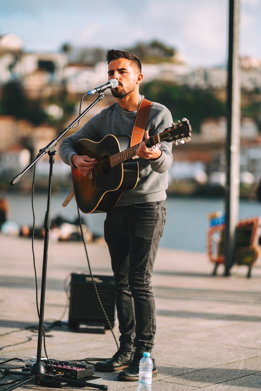 man singing while playing guitar at middle of street