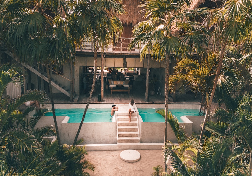 man and woman swimming at pool surrounded by trees