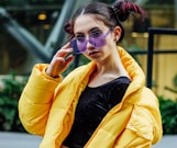 woman in yellow jacket with black inner shirt wearing purple sunglasses during daytime