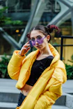 woman in yellow jacket with black inner shirt wearing purple sunglasses during daytime