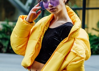 woman in yellow jacket with black inner shirt wearing purple sunglasses during daytime