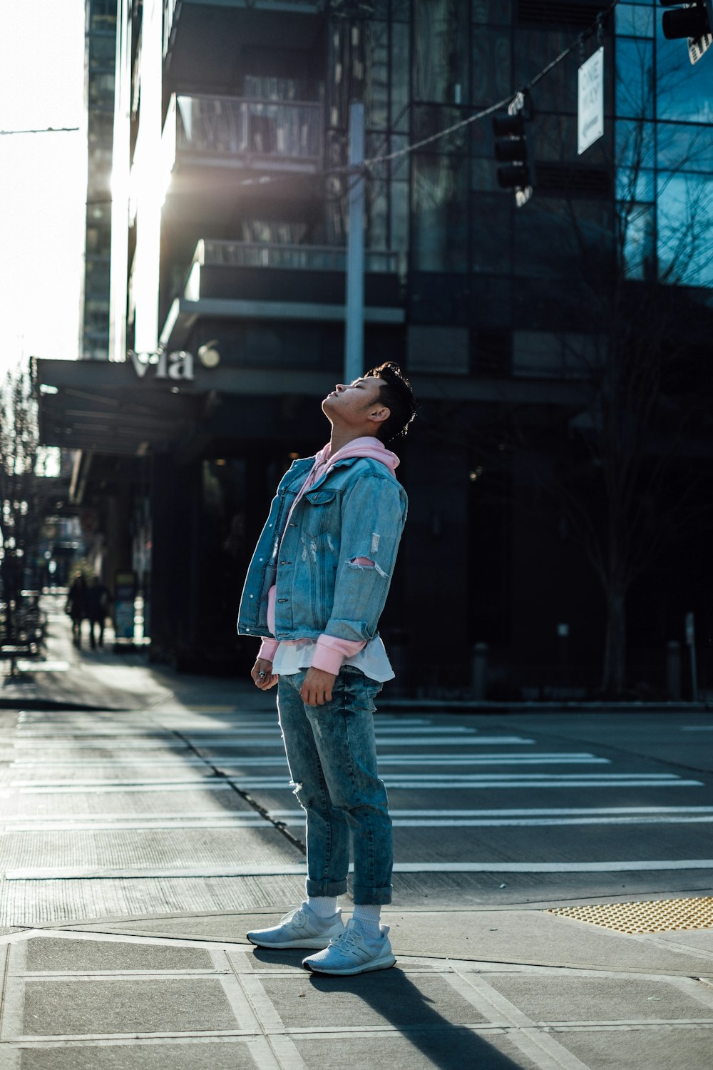 man in blue denim jacket standing on road during daytime