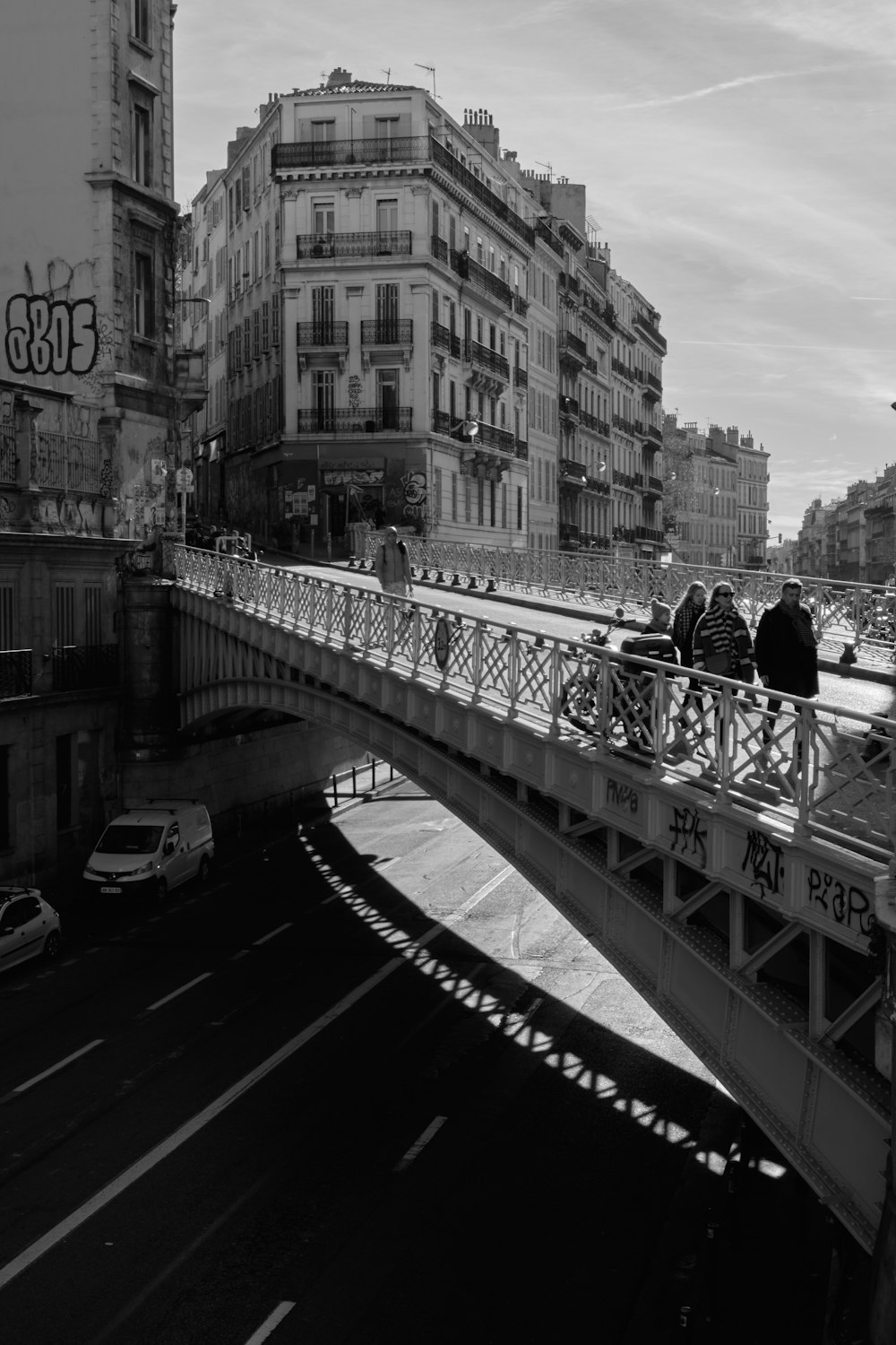 greyscale photo of people walking on bridge