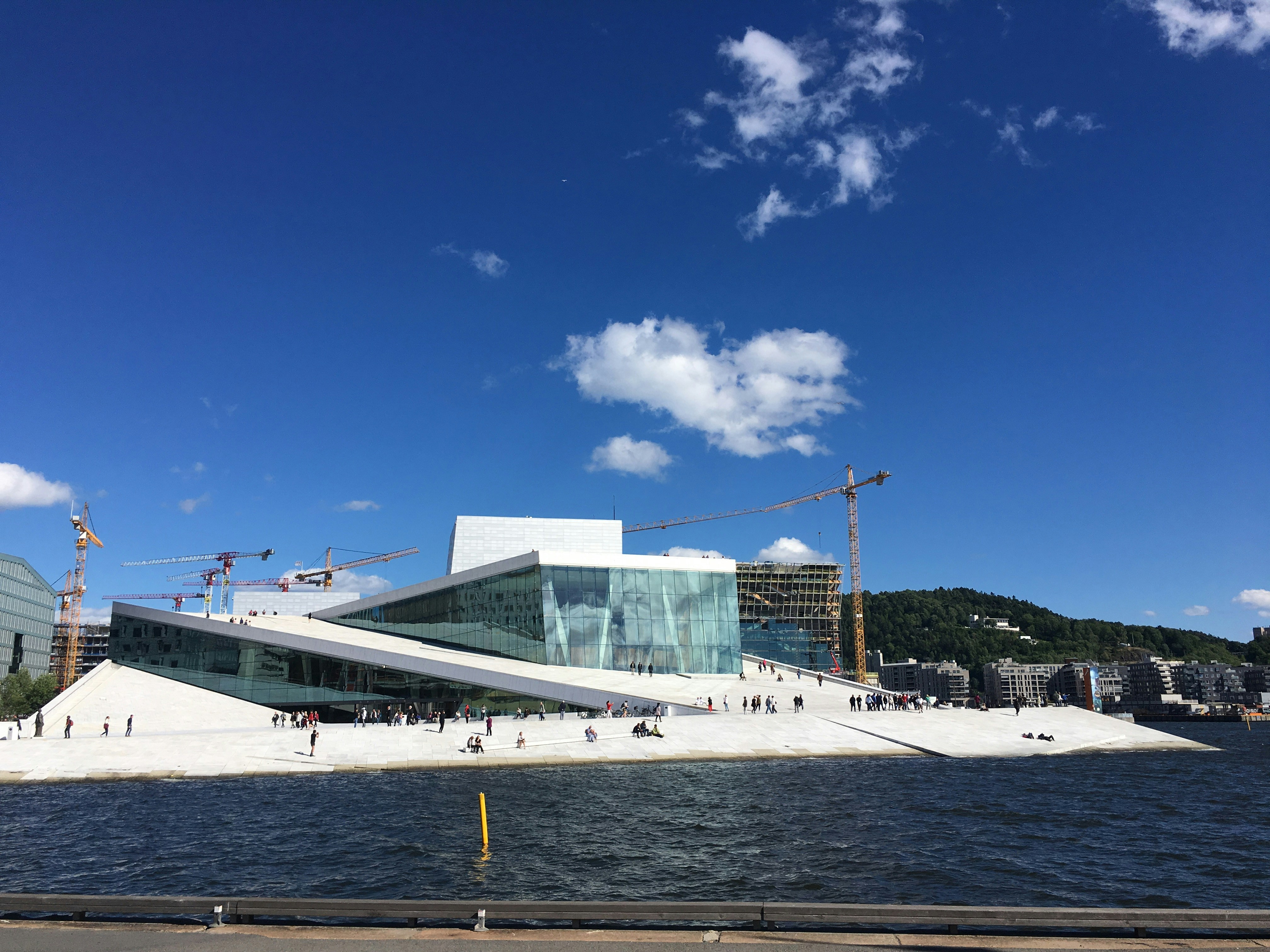people standing on snow near building and body of water during daytime