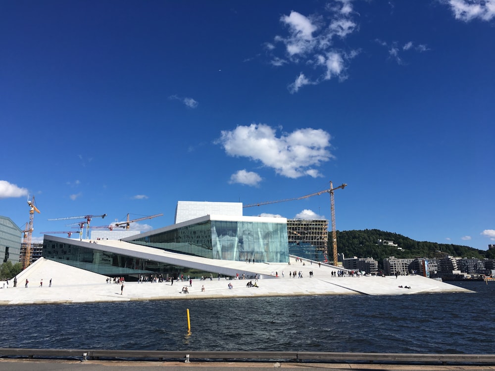 people standing on snow near building and body of water during daytime