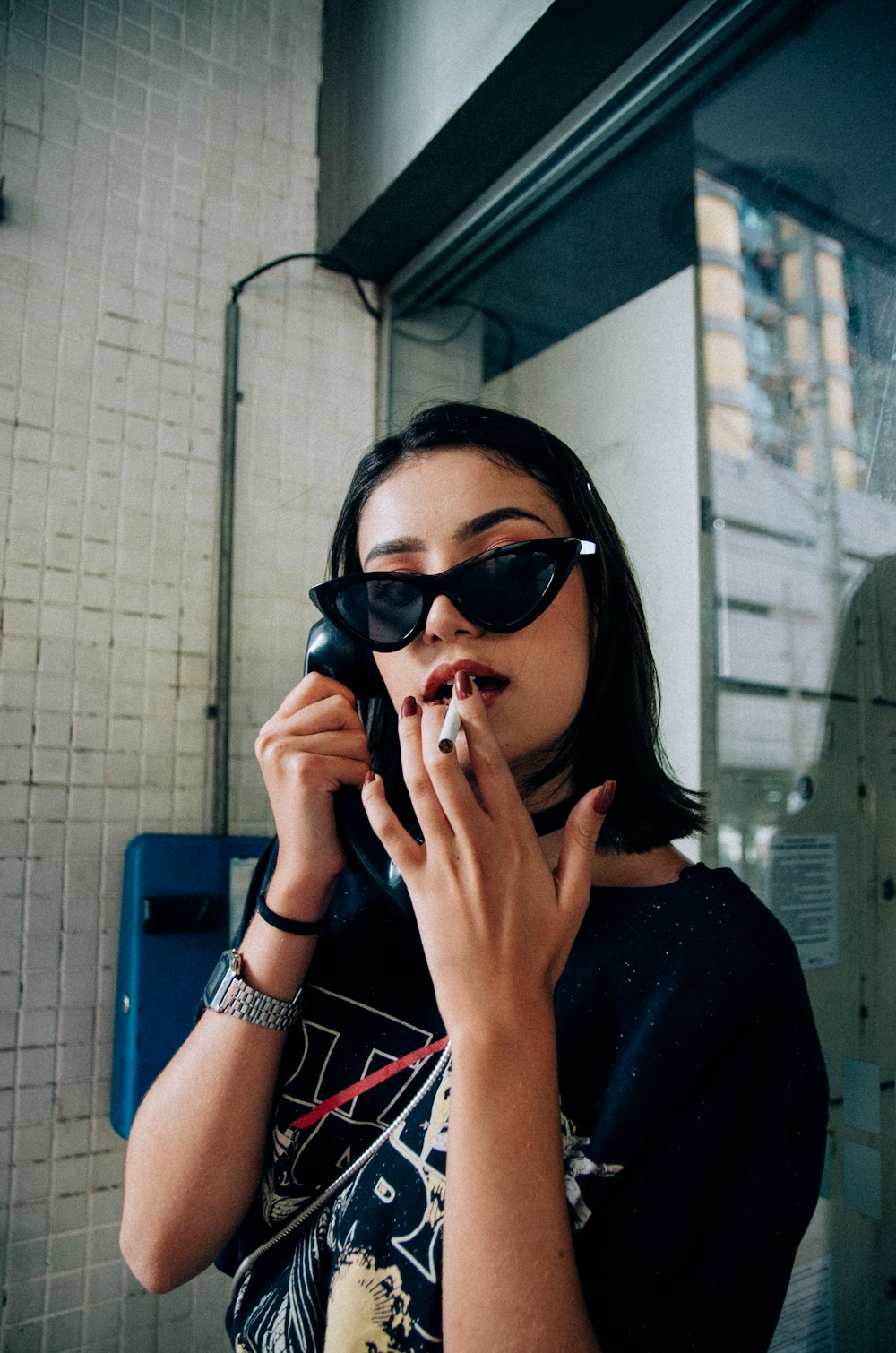 woman in black shirt holding telephone and cigarette