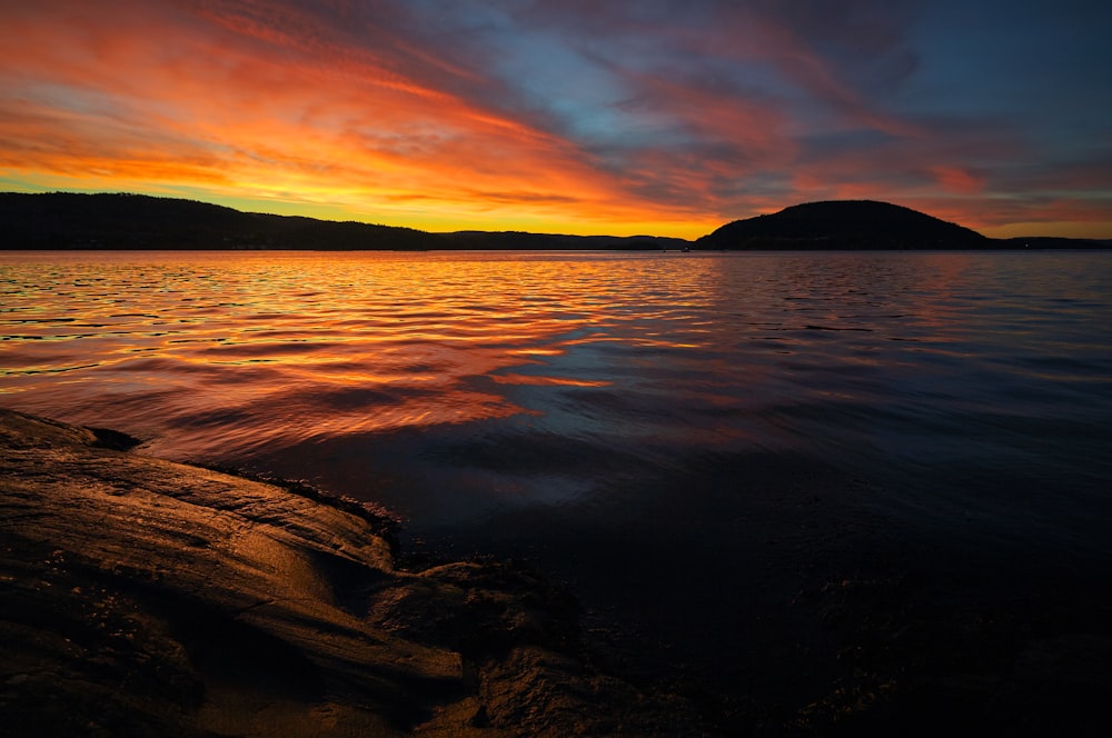 calm sea with silhouette mountain during sunset