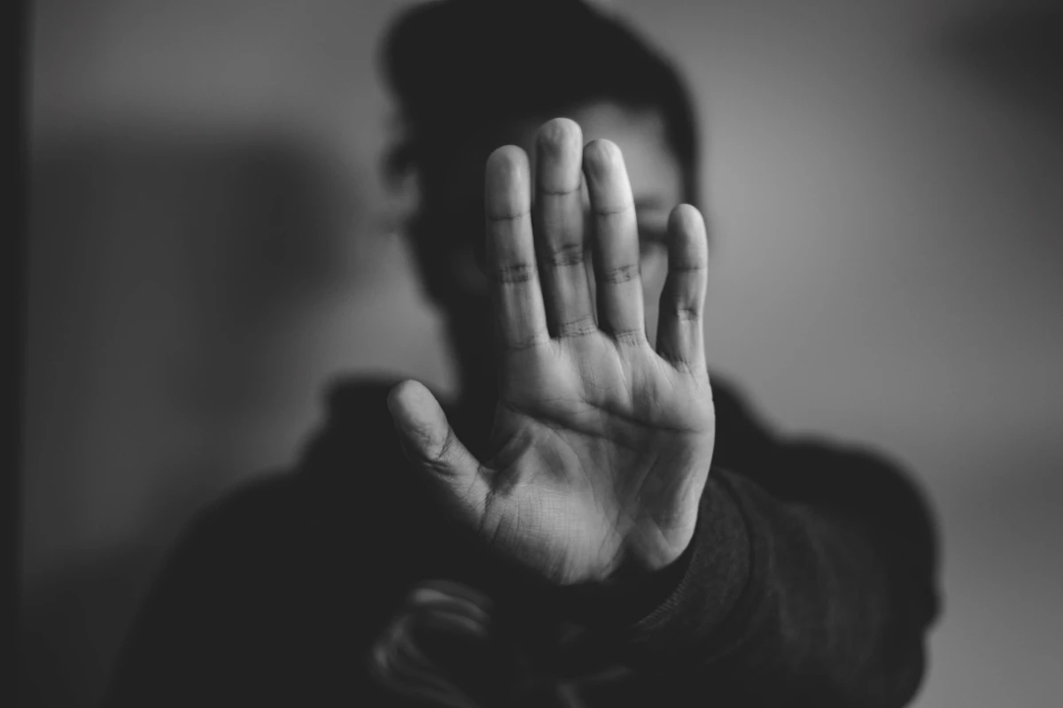 Dua tangan terangkat ke depan dalam gestur menahan atau membela diri