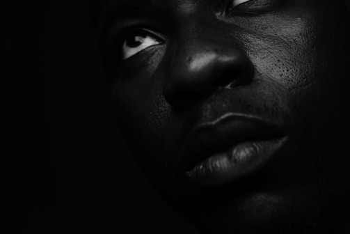 Black and white close-up portrait of a model wearing high-end couture, dramatic lighting emphasizes texture.