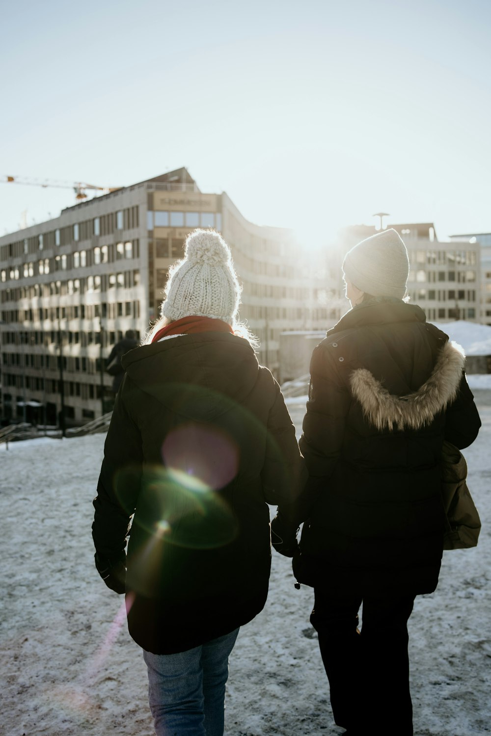 zwei Personen mit Jacke, die tagsüber auf einem schneebedeckten Feld spazieren gehen