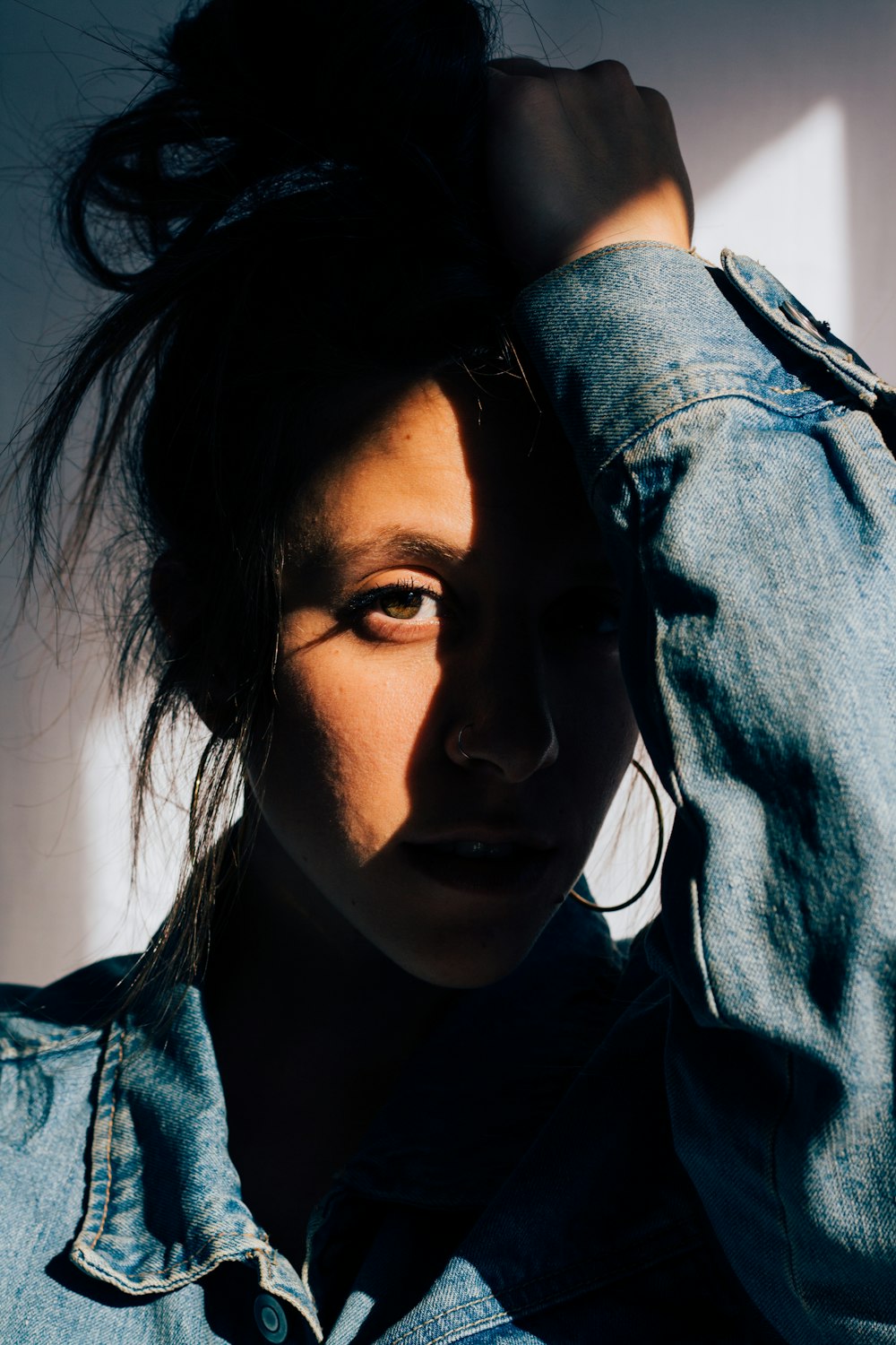 person in blue denim jacket holding head using left hand