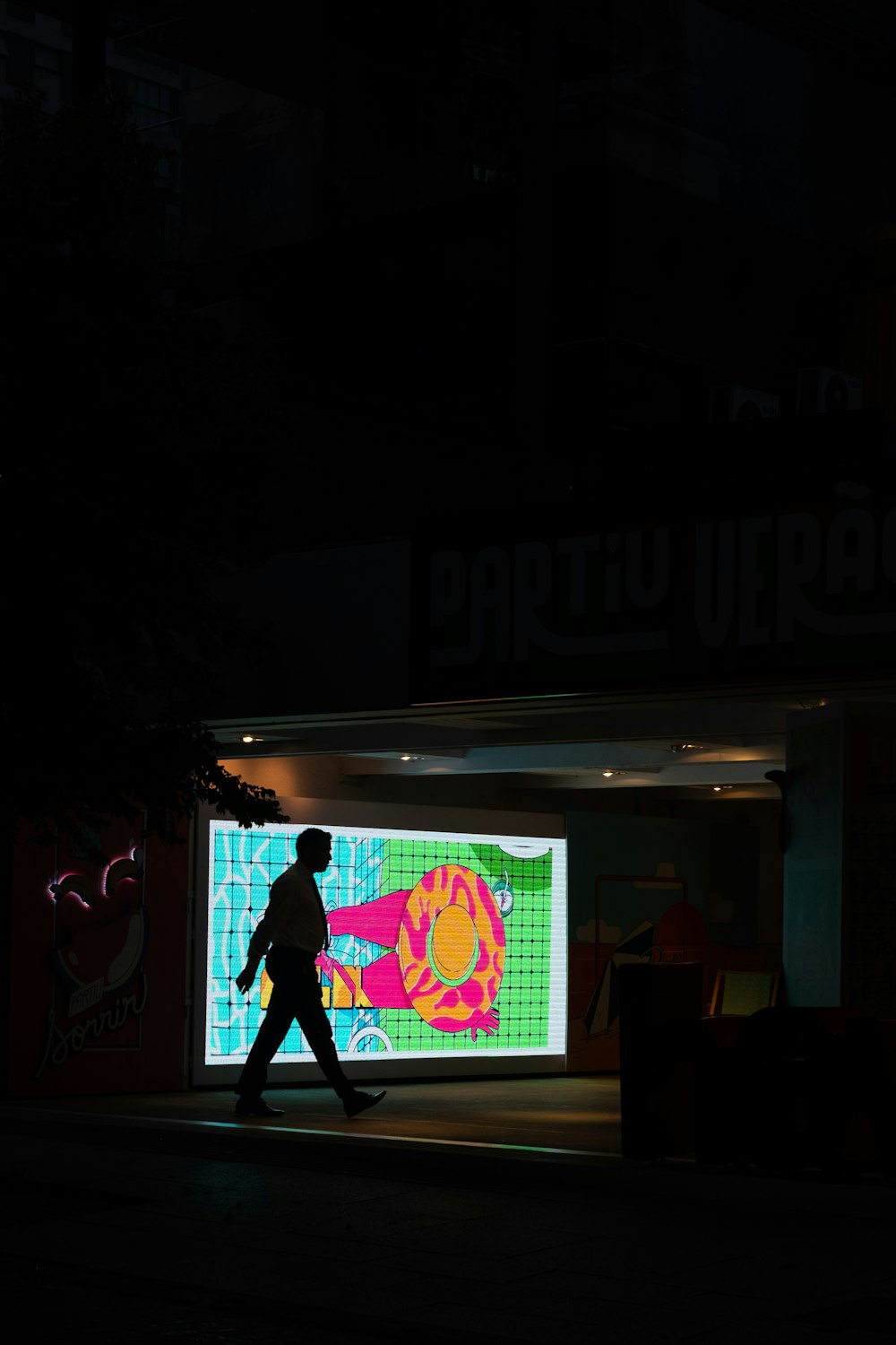 silhouette of man crossing near blue, pink and green light