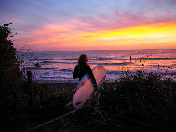 Woman with a surfboard at golden hour