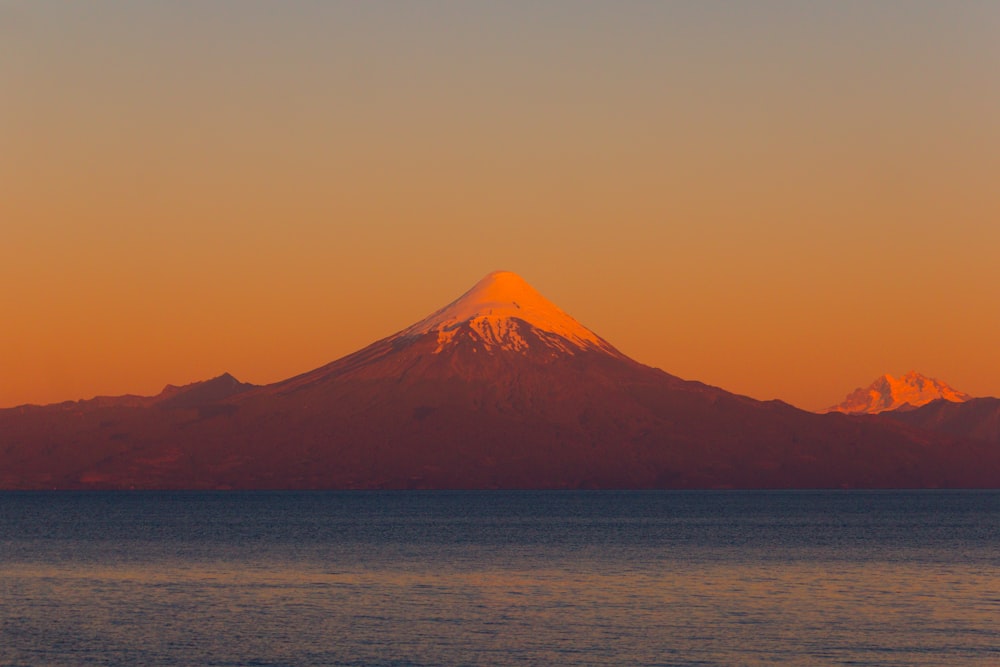 snow covered mountain near calm body of water