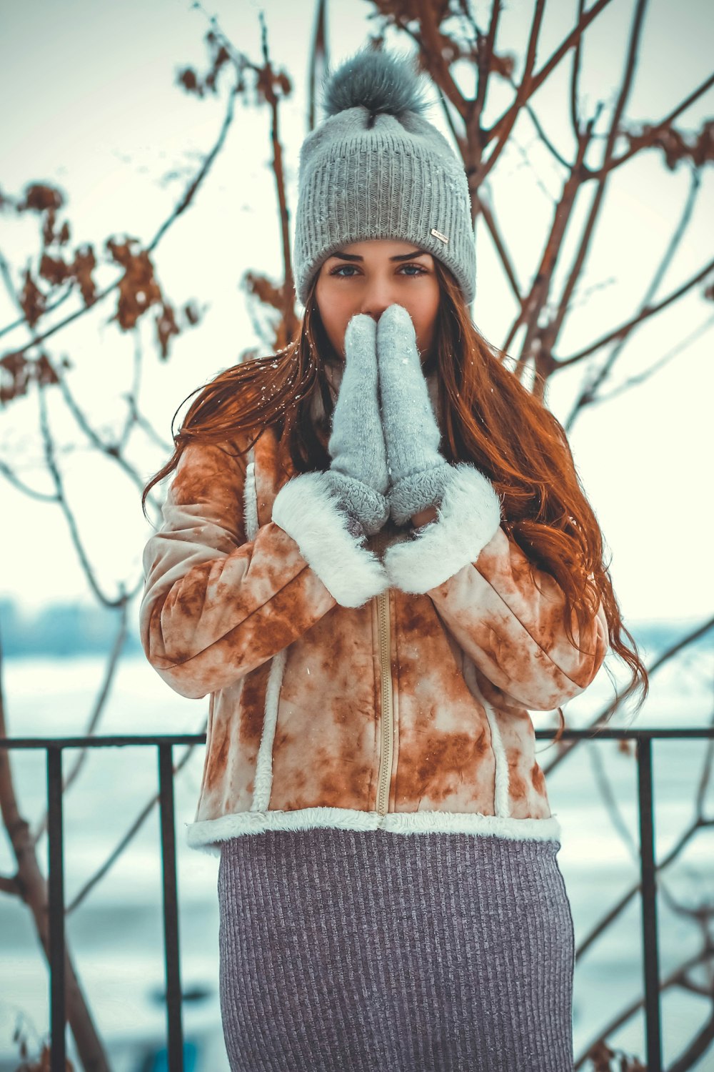 woman wearing brown jacket and gray knit cap standing near tree