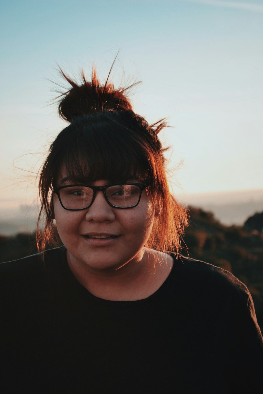 woman wearing eyeglasses smiling near mountains during daytime