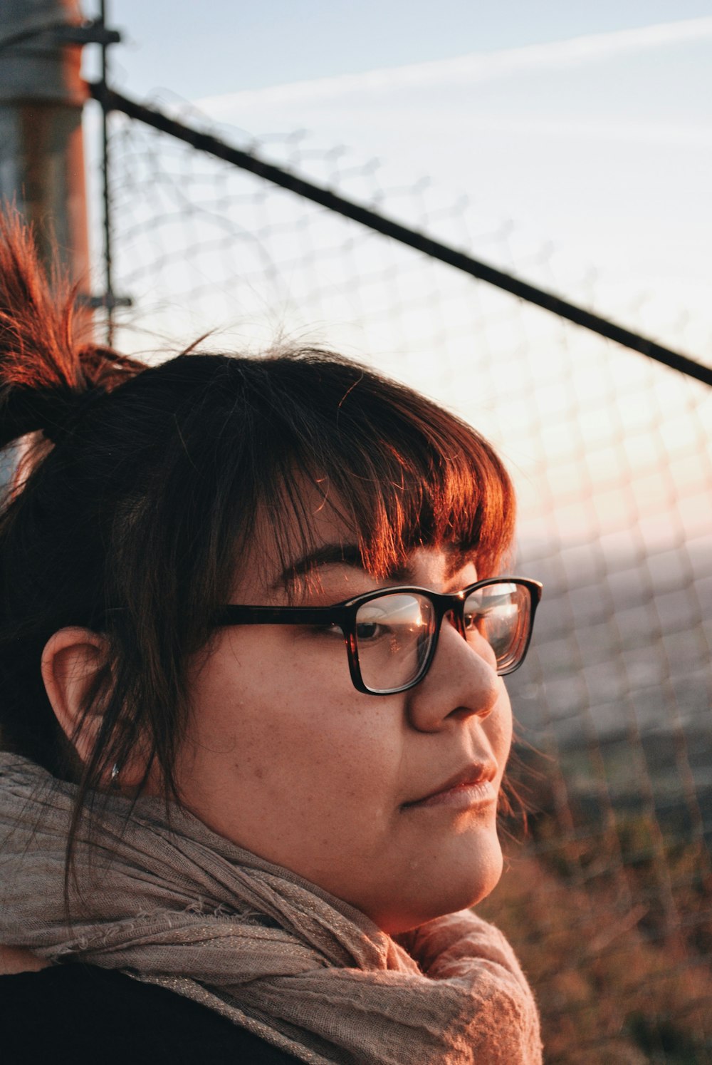 woman wearing eyeglasses standing near fence