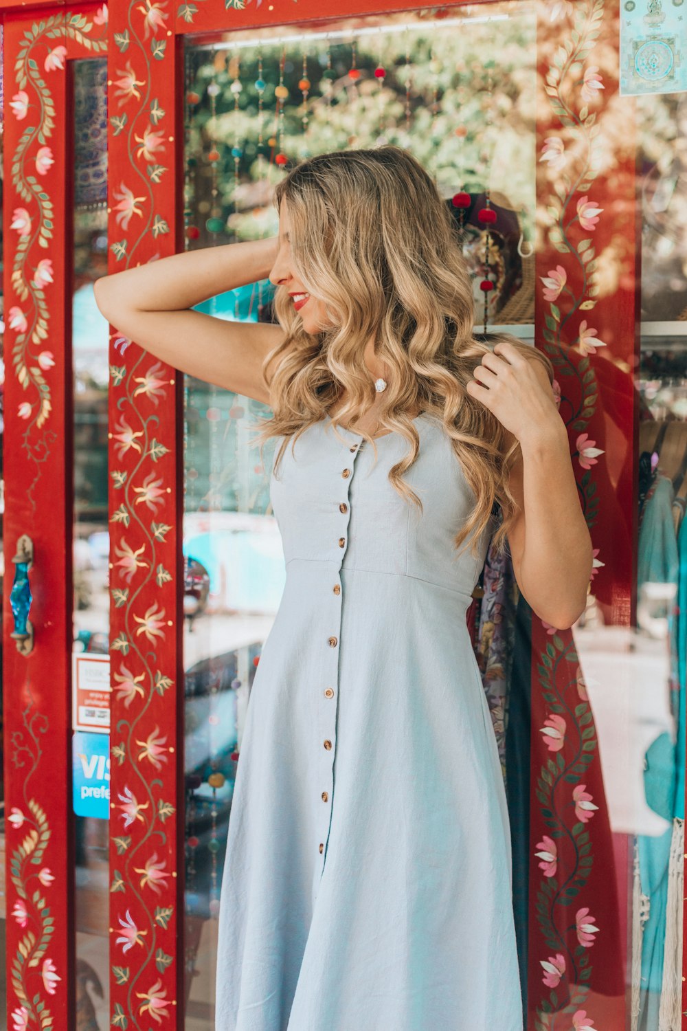 woman in blue tank dress leaning on glass wall