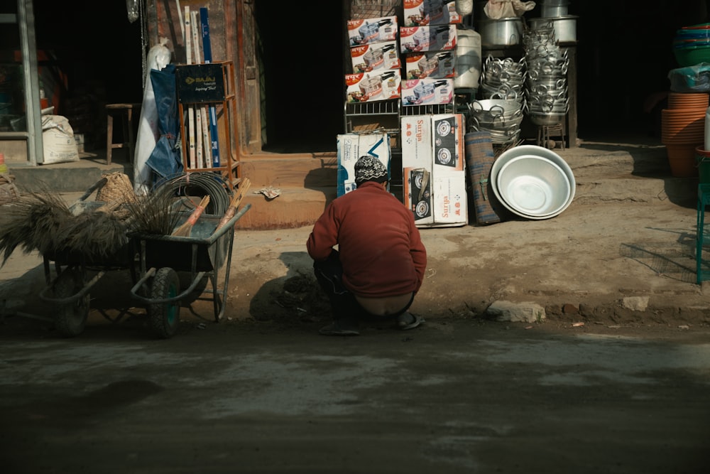 man sitting beside houseware store during daytime