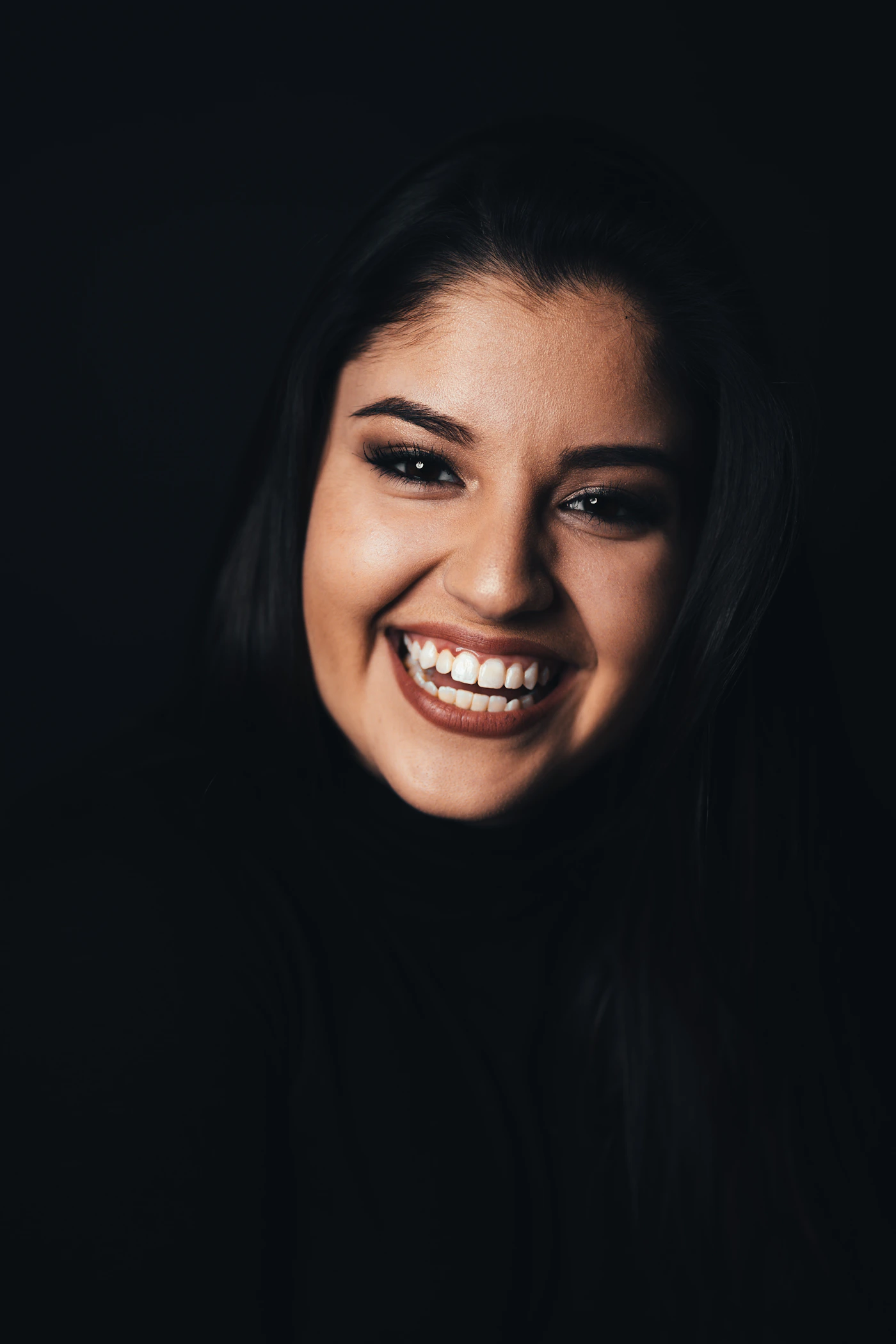 Close-up portrait of a young woman with a genuine, natural smile and smooth skin during preventative micro-dose Botox treatment review