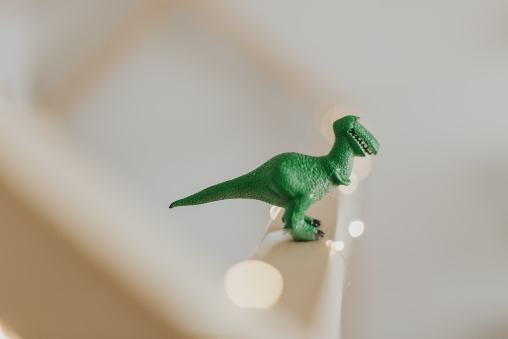 green T-rex toy on white stair