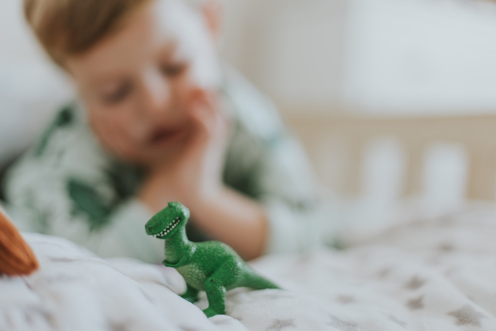 forced-perspective photography of green dinosaur figurine