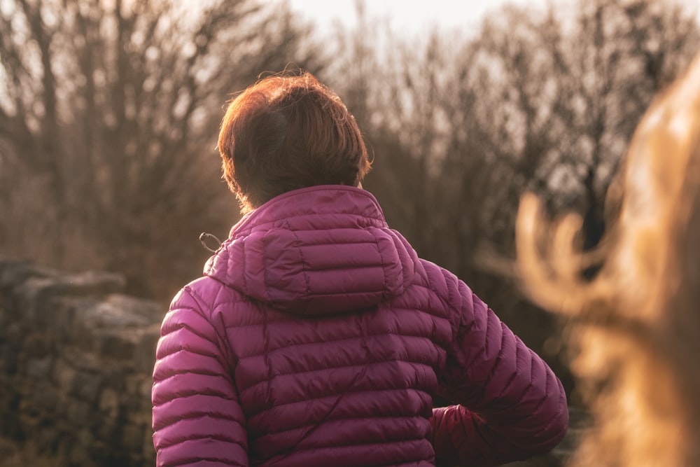 person wearing purple jacket standing near black wall